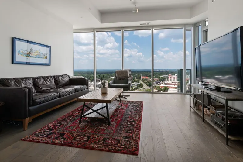 A condo living room high above the city, with a red area rug and floor-to-ceiling windows
