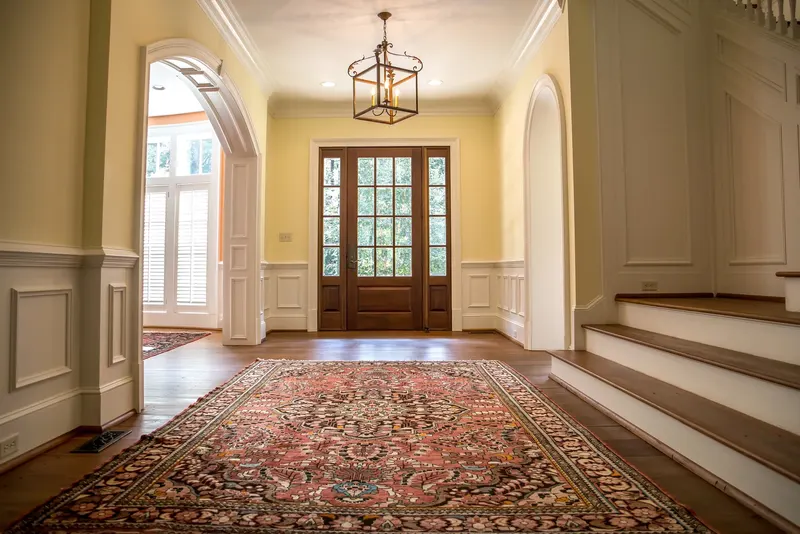 A patterned rug in an entry hall at the foot of a staircase